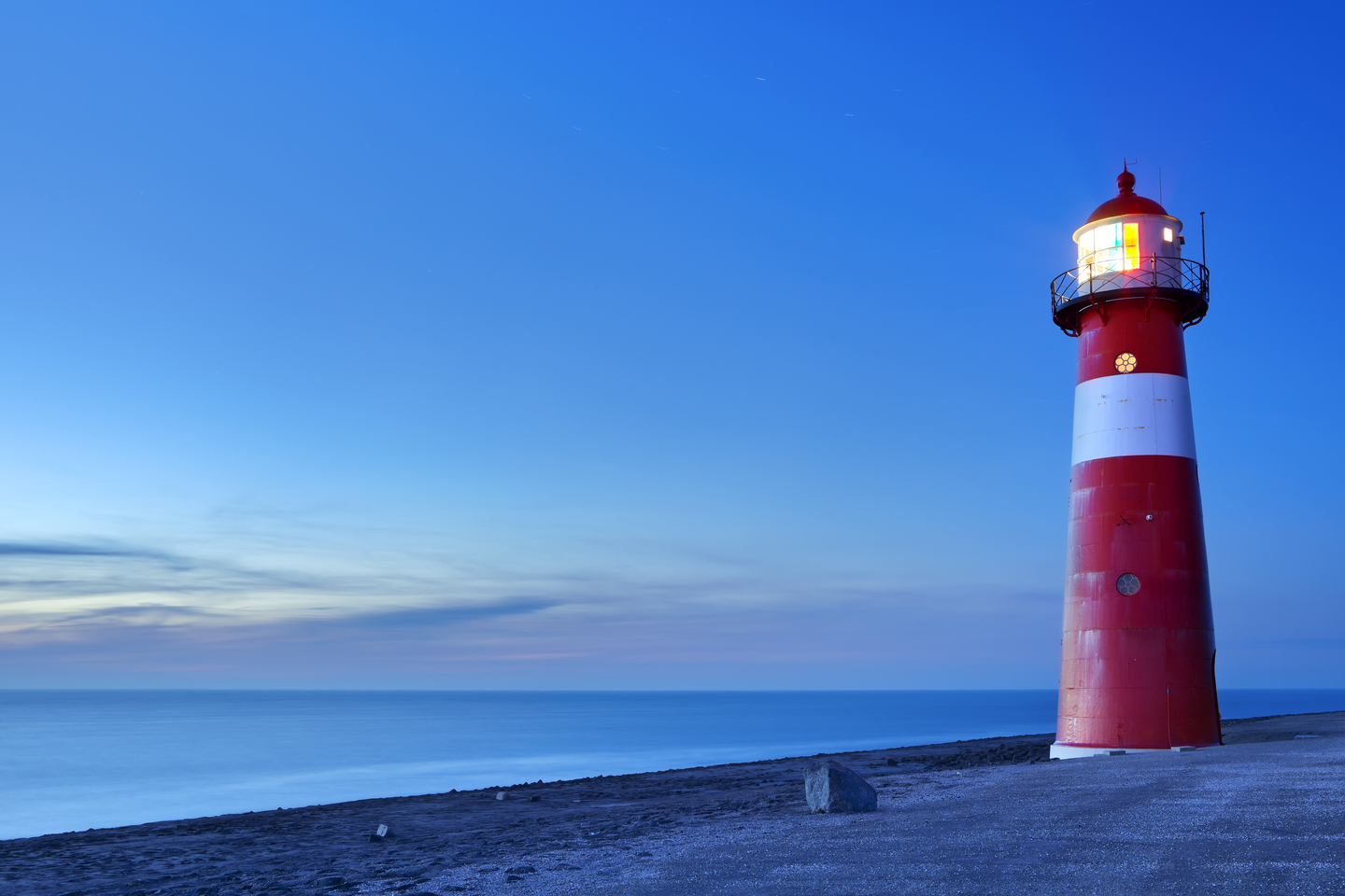 Red and white lighthouse on the sea at sunset